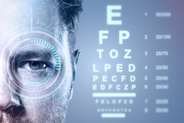 Closeup of male eye with digital interface and vision test chart in background on blue gradient for...