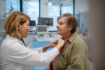 Geriatrician doctor examining elderly patient with stethoscope.