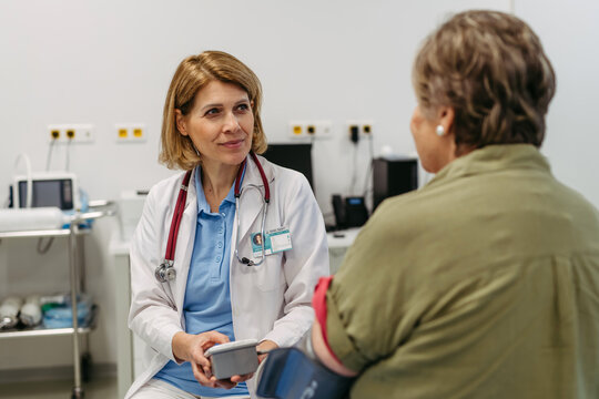 Elderly female patient undergoing blood pressure test at routine check-up.