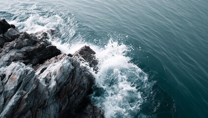 A dramatic coastal scene unfolds where dark cliffs loom over a turbulent sea as foamy waves collide with the rocky shoreline beneath a dense, overcast sky
