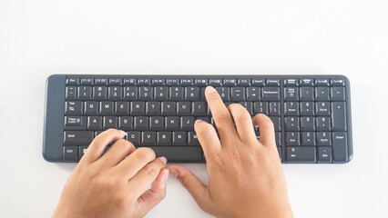 Top view of fingers typing on a black modern wireless computer keyboard isolated on white background
