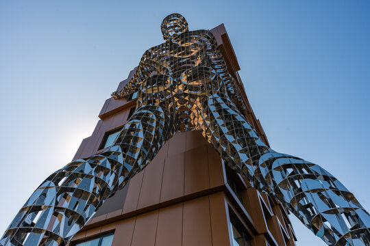 Prague, Czech Republic - September 21, 2024: Upward view of mirrored Lilith sculpture by Czech artist David Cerny integrated into the facade of a contemporary building in Karlin district