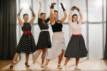 Four pinup dancers raising arms in 1950s style choreography