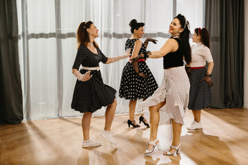 Four pinup dancers wearing polka dots swinging in dance studio © dsheremeta