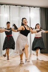 Naklejka premium Women wearing polka dot dresses and black gloves dancing in 1950s style