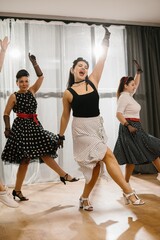 Women wearing polka dots dresses and gloves dancing 1950s style swing