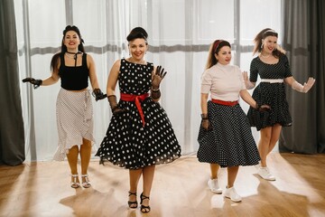 Four pinup women dancing gracefully in 1950s style dresses