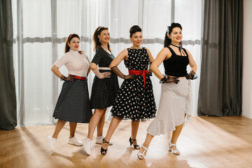 Four pinup women wearing polka dots posing in dance studio