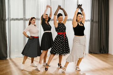 Four women dancing rock and roll wearing polka dots dresses and skirts