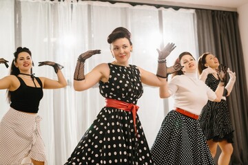 Pinup dancers wearing polka dots swinging in 1950s style choreography