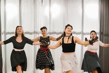 Four pinup dancers wearing fifties style polka dot dresses and performing a choreography
