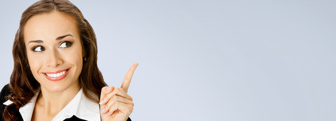 Banner wide image - happy smile businesswoman showing pointing advertise. Business woman executive employee bank manager, isolated against grey gray wall background with free ad text space