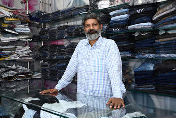 Indian shopkeeper showing clothes in store market