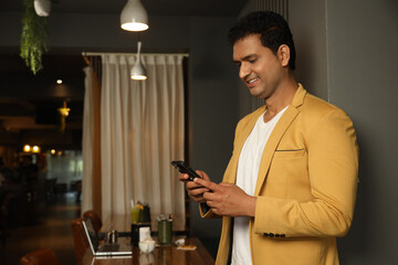 Indian handsome man using mobile phone at cafe. wearing formal suit. Concept : Mobile Banking Sectors.