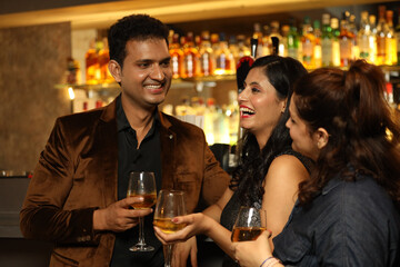 Indian loving couple toasting cocktail and beer glass at bar counter. Couple celebrating anniversary 