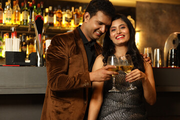 Indian loving couple toasting cocktail and beer glass at bar counter. Couple celebrating anniversary 