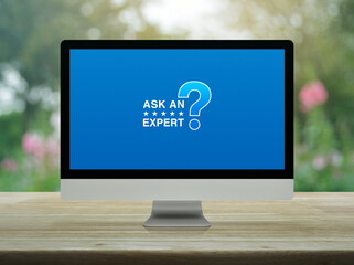 Ask an expert with star and question mark sign icon on desktop modern computer monitor screen on wooden table over blur park, Technology communication online concept
