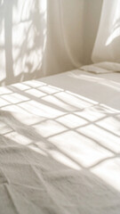 Soft Sunlight Creates Delicate Shadows Across a White Bed in a Serene Indoor Space During the Morning Hours