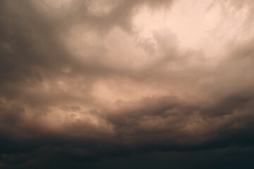 Obraz premium Dramatic thunderstorm with dark clouds in the evening. Dramatic cloudscape featuring dark, moody clouds with a bright, fiery orange glow