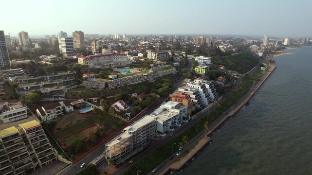 Panoramic aerial push along Maputo&rsquo;s Sommerschield coastline, revealing oceanfront roads, modern villas, and tropical urban life