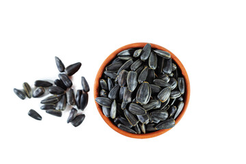 Heap of sunflower seeds in clay bowl isolated on white background. Top view.