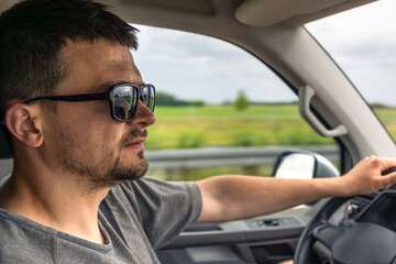Driver profile. Man behind the wheel. Sunglasses in vehicle