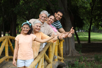 Indian happy family showing thumbs up while having fun and enjoying in summer park. Concept happy family lifestyle.