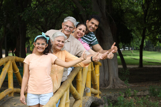 Indian happy family showing thumbs up while having fun and enjoying in summer park. Concept happy family lifestyle.