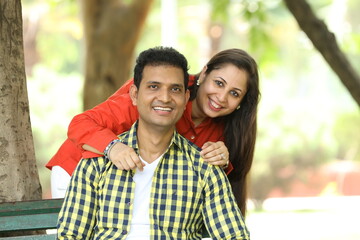 Obraz premium Indian happy young couple looking at the camera. Romantic and Attractive happy couple in love, fun, hugging outside, relaxing, spending leisure time together, relationship and people concept.