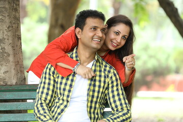 Naklejka premium Indian happy young couple pointing finger at park Romantic and Attractive happy couple in love, fun, hugging outside, relaxing, spending leisure time together, relationship and people concept.