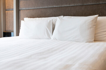 Bright clean comfortable bedroom interior white bed linen bedding soft pillows plush duvet light window contemporary design home comfort hotel apartment space.