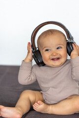 Smiling baby with headphones. Music and joy. Cozy childhood moment
