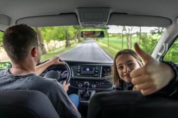 Girl thumbs up. Joyful car ride. Passenger and driver.