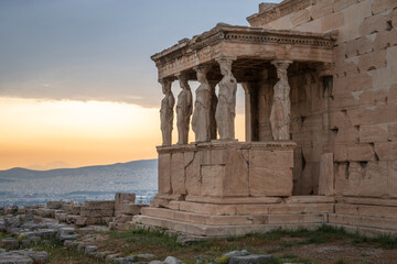 The Caryatides, female statues in the Acropolis of Athens, Greece, framed by a vibrant sunset