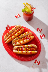 Top view of Canada Day hot dogs decorated with Canadian flags on a light background., top view,...