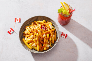 Canadian poutine with fries, cheese curds, and gravy in a bowl, decorated with Canadian flags, top view, copy space.
