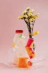 Conceptual balancing still life with plastic and flower on pink, theme of recycling, waste...