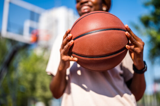 Close up of young woman holding basketball. She is practicing basketball on sunny day.