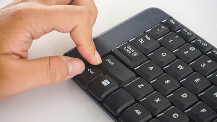 Finger pressing letter A button on a black wireless computer keyboard isolated on white background