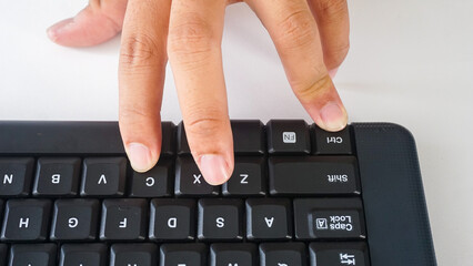 Fingers typing on a black modern wireless computer keyboard isolated on white background