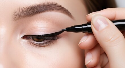 Obraz premium Applying black eyeliner with pen on eye. Macro beauty close up. Eye makeup and cosmetics concept. Image for banner, poster, wallpaper and advertisement