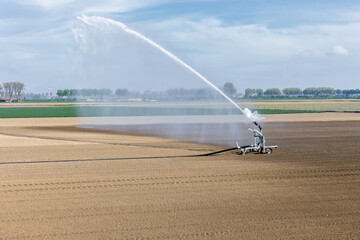Waterkanon spuit water over droge akker, door klimaatverandering valt er vaker te weinig regenwater op het land