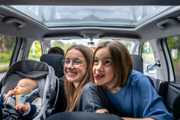 Happy kids in car. Playful faces. Baby in car seat.