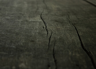 A close-up of the texture of an old, dark wooden surface with cracks. A rustic and dramatic...