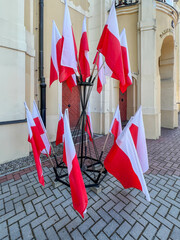 Polish flags in a stand in front of a building