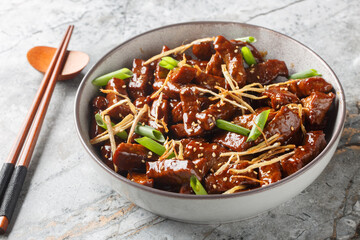 Ginger beef in spicy sweet sauce with sesame and green onions close-up in a bowl on the table. Horizontal