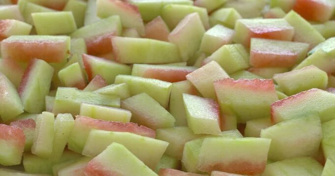 Peeled watermelon rind chunks background texture. Watermelon rind is edible after heat treatment (stir-fry, braise, or cook). Zero waste food concept. Selective focus, table spin.