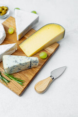 Assortment of cheeses displayed on a wooden board with garnish