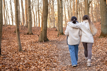 Two female friends on a walk in the forest. Friends walking through the forest. People in nature.