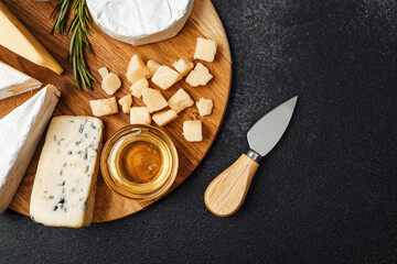 Cheese platter featuring various types and honey on a wooden board
